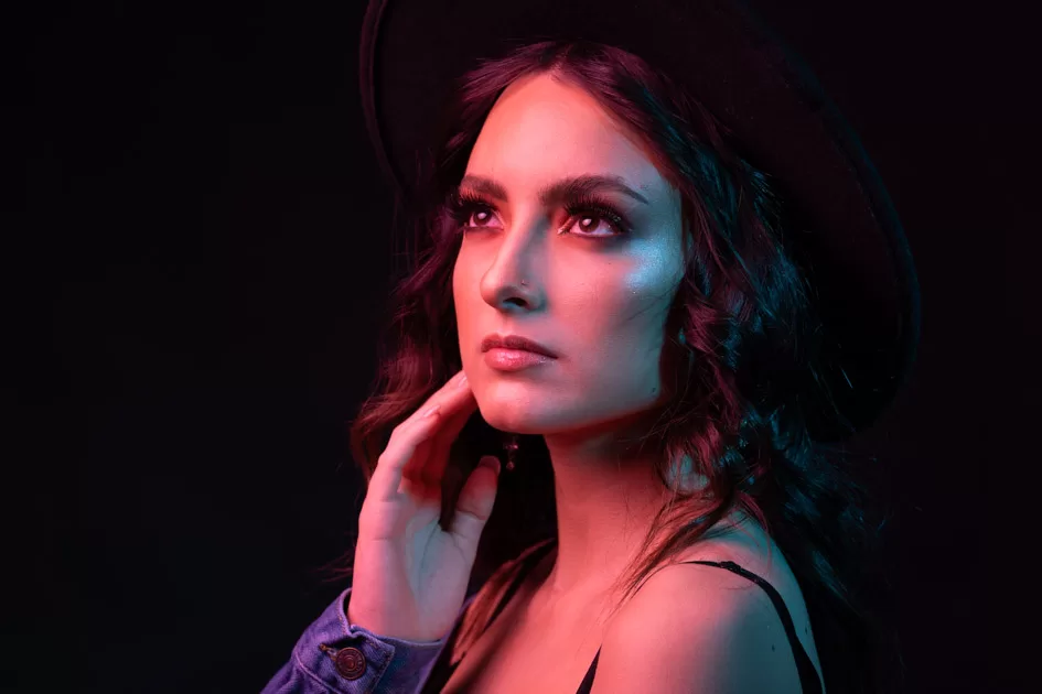 Elegant woman in a hat under colorful lighting